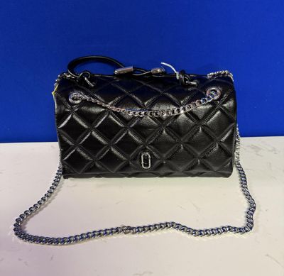 a black quilted purse on a white table with a blue background