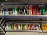 many pens and pencils on the shelves in the office