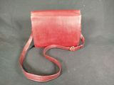 red leather purse with strap on a black background