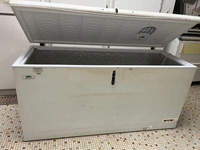 un congélateur coffre blanc posé sur un sol carrelé