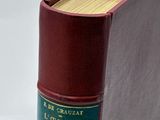 an old book with a red cover sitting on top of a white table