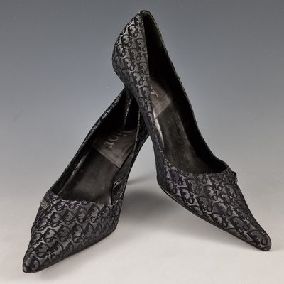 une paire de chaussures en peau de serpent noire posée sur une surface blanche
