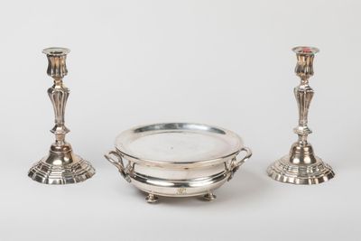 two silver candlesticks and a bowl on a white background