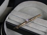 une pince à cravate en or sertie d'un diamant, dans un étui