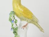a yellow bird sitting on top of a white vase