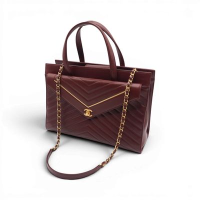 a red handbag with a chain strap and a gold clasp