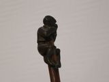 a statue of a man sitting on top of a wooden pole