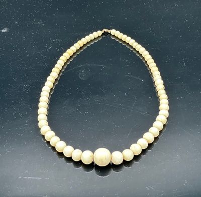 a close up of a necklace with pearls on a black surface