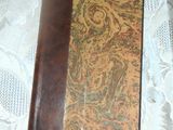 an old book with a brown cover sitting on a lace tablecloth
