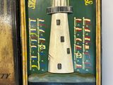 painting of a lighthouse on a shelf next to a metal box