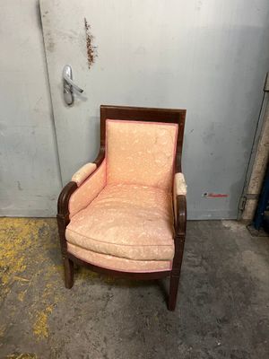 une vieille chaise dont l'assise est recouverte d'un tissu rose