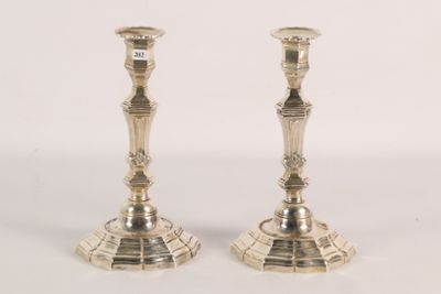 pair of silver candlesticks on a white surface with a white background