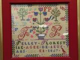a framed picture of a cross stitch sample with a red frame and gold trim