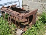 une machine rouillée abandonnée dans l'herbe près d'un bâtiment