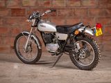 a silver motorcycle parked in front of a brick wall