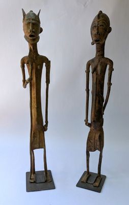 deux statues en bois représentant un homme et une femme debout l'un à côté de l'autre
