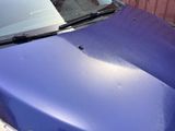 a blue car that is parked next to a wooden fence