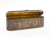 an old silver box with a gold lid on a white surface