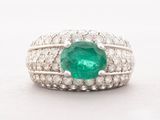 a close up of a ring with a green stone surrounded by white diamonds
