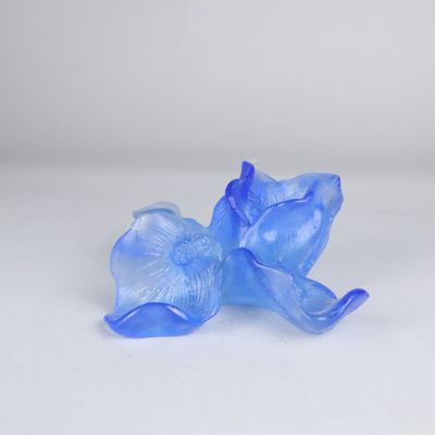 une figurine en verre bleue représentant un chat posée sur une surface blanche