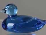a blue glass duck sitting on top of a table
