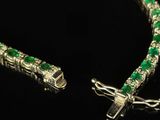 a close up of a bracelet with green stones on a black surface