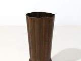 une image représentant un vase marron posé sur une surface blanche