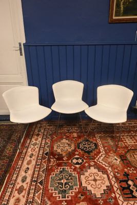 three white chairs sitting on top of a red rug in a room