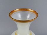 a white vase with a gold rim sitting on a table