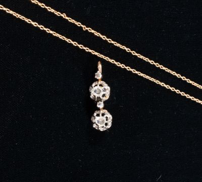 a gold necklace with two small white diamonds on a black background