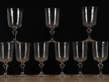 six empty wine glasses are lined up on a wooden table