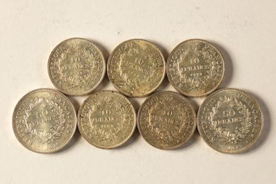 six pièces de six livres sterling sont disposées en ligne sur une surface blanche