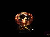 a close up of an orange diamond on a black surface