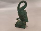 statue représentant un oiseau posé sur un rocher, sur fond blanc