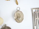 a silver locke with a picture on it next to other silver items