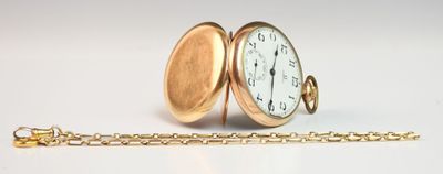 une montre de poche en or avec une chaîne, posée sur une surface blanche