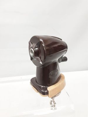 un objet marron posé sur un socle, sur une surface blanche