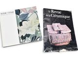 two books on a white surface with a flower design