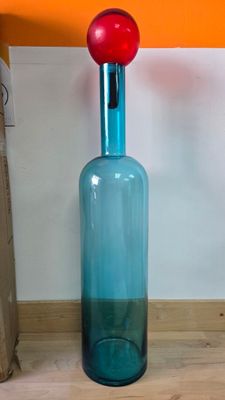 une bouteille en verre bleue surmontée d'une boule rouge