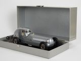 une petite voiture argentée dans une boîte argentée posée sur une surface blanche