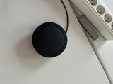 a black speaker sitting on a white surface next to a power strip