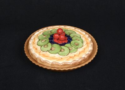 un petit gâteau garni de kiwis et de cerises