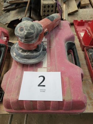 une photo d'une boîte à outils rouge sur laquelle est posée une ponceuse