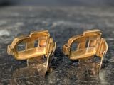 a pair of gold cuff earrings sitting on a table