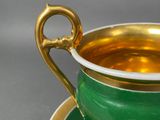 a green and gold cup and saucer on a saucer