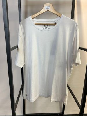 un t-shirt blanc suspendu à un portant dans une pièce