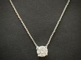 a necklace with a diamond on a chain on a black surface