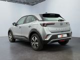 the rear end of a silver car in a white room