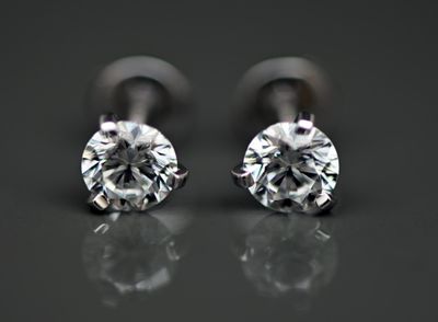 une paire de boucles d'oreilles en diamant posée sur une surface réfléchissante