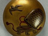 a gold ornament with a bird and a birdcage on it